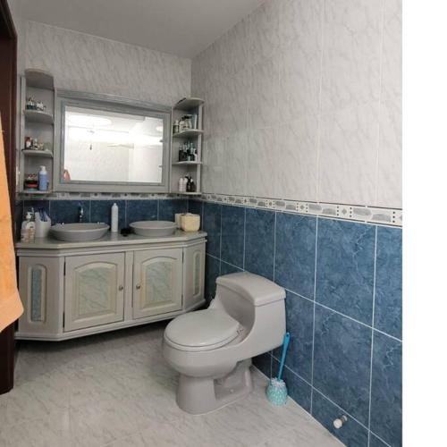 a bathroom with a toilet and two sinks and a mirror at Hermosa Casa con doble garaje amoblada en el Albergue in Club del Comercio