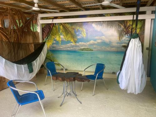 una mesa y sillas en una habitación con un mural en LES HAMACS AUX SAINTES BIS en Terre-de-Haut