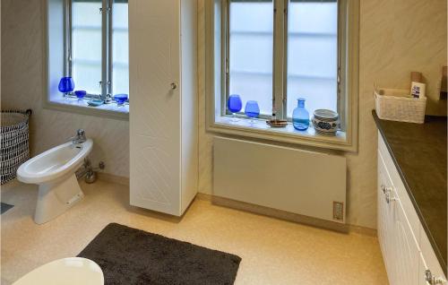 a bathroom with a toilet and a window with blue vases at Lovely Home In Hjltevad With House Sea View in Hjältevad