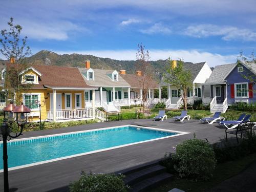 a house with a swimming pool in the yard at Vermont Khao Yai Resort in Ban Na Sok