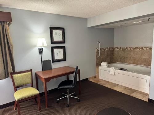 ein Hotelzimmer mit einem Schreibtisch und einer Badewanne in der Unterkunft AmericInn by Wyndham Stillwater in Stillwater
