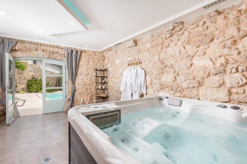 uma grande banheira num quarto com uma parede de pedra em Villa Ivka em Tribalj