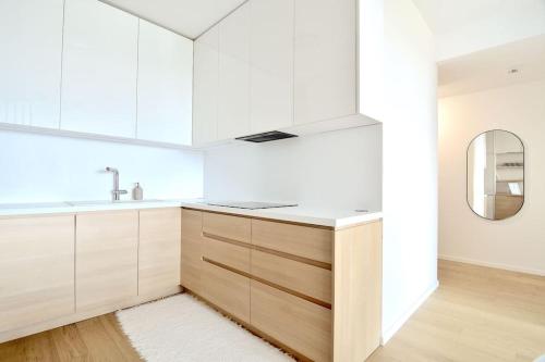 a kitchen with white cabinets and a sink and a mirror at Downtown Charm with free parking spot in Bratislava