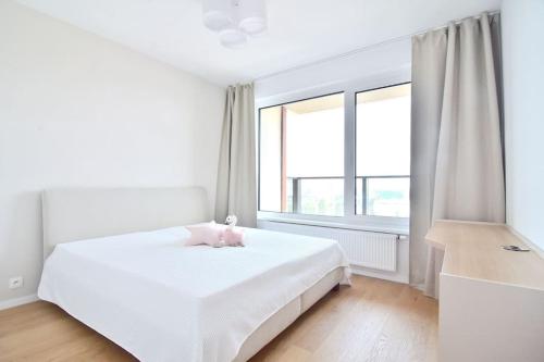 a white bedroom with a white bed and a window at Downtown Charm with free parking spot in Bratislava