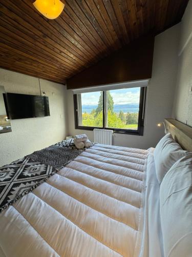 - un grand lit dans une chambre avec une grande fenêtre dans l'établissement El Residencial Bariloche, à San Carlos de Bariloche