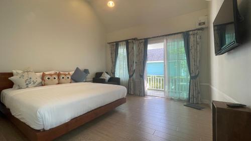 a bedroom with a bed and a large window at Vermont Khao Yai Resort in Ban Na Sok