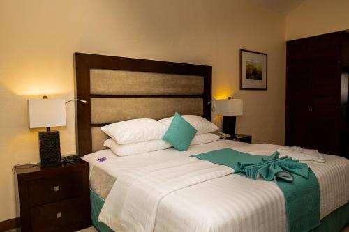 a bedroom with a large bed with white sheets and blue pillows at Hotel Villa Mercedes Palenque in Palenque