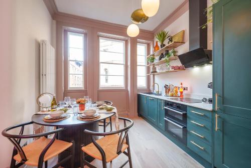 The Half Angel - 1 Bedroom Apartment in Central Bristol by Mint Stays في بريستول: مطبخ مع دواليب زرقاء وطاولة مع كراسي