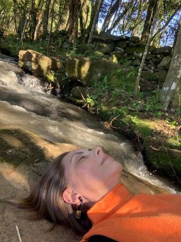 a woman laying on the ground next to a river at L'esperienza - Pousada Butique - Ecoturismo in Nova Petrópolis