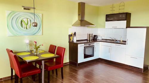 a kitchen with a table and red chairs at Haus Am Strand in Juliusruh