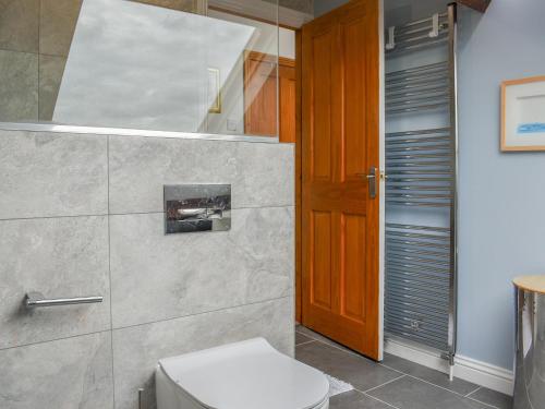 a bathroom with a toilet and a wooden door at Oak Tree Cottage in Brierfield