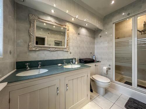 uma casa de banho com 2 lavatórios, um WC e um espelho. em Moulsham House em Stoke Ferry