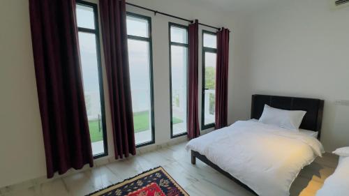 Schlafzimmer mit einem Bett und großen Fenstern in der Unterkunft Wadi Shab Beach Resort in Ţīwī