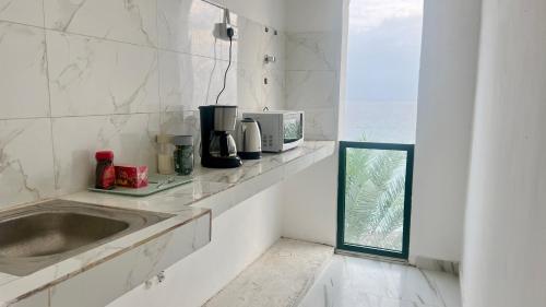 eine Küche mit einer Spüle und einer Mikrowelle in der Unterkunft Wadi Shab Beach Resort in Ţīwī