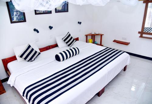 a bedroom with a large white bed with black and white pillows at Dawn View Home Stay in Ella
