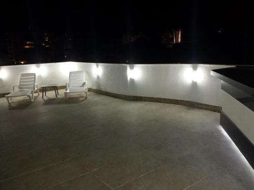 two chairs and a table on a rooftop at night at Lindo! Novo ! Perto do Consulado Americano e Shopping! in Porto Alegre