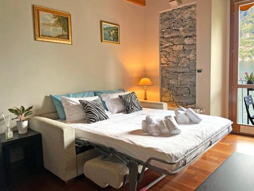 a large bed in a room with a stone wall at Balcony On The Lake - Free Parking, Lake view in Laglio