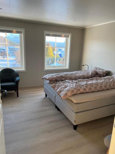 a bedroom with two beds and a chair and two windows at Villaveien in Sortland