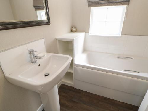ein weißes Badezimmer mit einem Waschbecken und einer Badewanne in der Unterkunft Emmerdale Lodge in Yarm