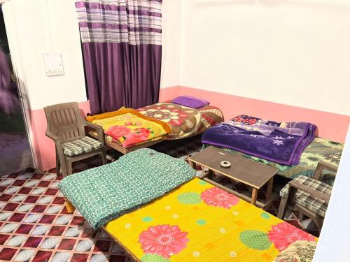 um quarto com três camas e uma mesa e cadeiras em Baba hostel em Pushkar