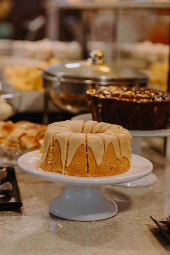a cake on a white plate on a table with other cakes at Lago Da Palma in Palmas