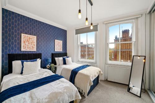 1 dormitorio con 2 camas y 2 ventanas en Delightful Flat in London - Sleeps 6 en Londres