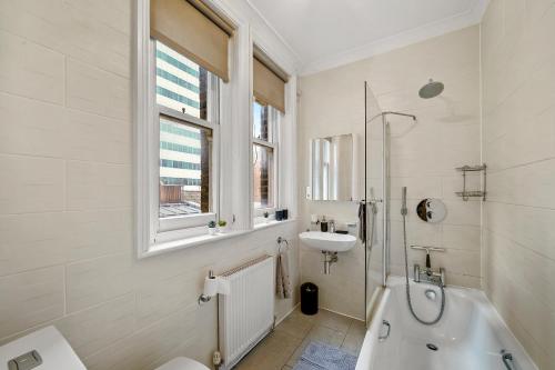 Delightful Flat in London - Sleeps 6 في لندن: حمام أبيض مع حوض وحوض استحمام