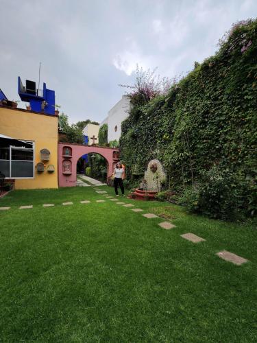 a person standing in a yard next to a wall at Maria Del Alma House in Mexico City