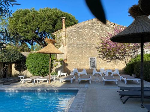 uma piscina com cadeiras e um guarda-sol ao lado de um edifício em Hotel du Soleil et Spa em Saint-Rémy-de-Provence