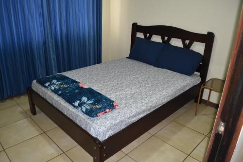 Una cama con almohadas azules y una manta azul. en SERENITY HOME H Y M en Turrialba