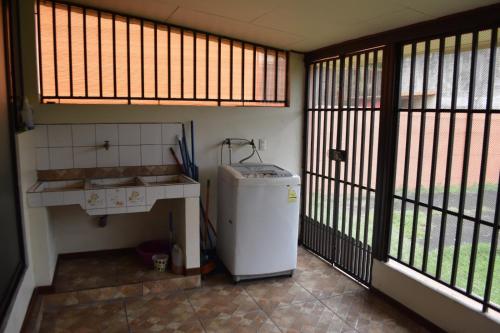 a room with a small refrigerator in a room with windows at SERENITY HOME H Y M in Turrialba