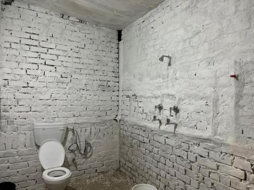 a bathroom with a toilet and a white brick wall at Baba hostel in Pushkar