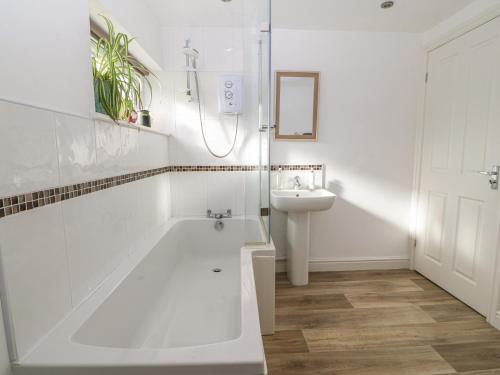 a white bathroom with a tub and a sink at The Bell Apartment in Cemaes Bay