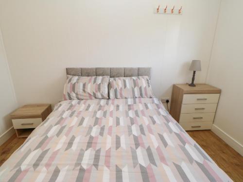 a bed with a pink and grey comforter in a bedroom at Nidderdale Pod in Yarm