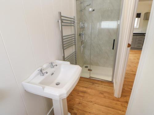a white bathroom with a sink and a shower at Ryedale Pod in Yarm