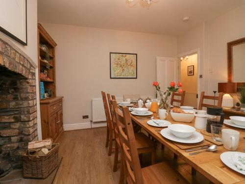 a dining room with a table with chairs and a fireplace at Heatherlea in Keswick
