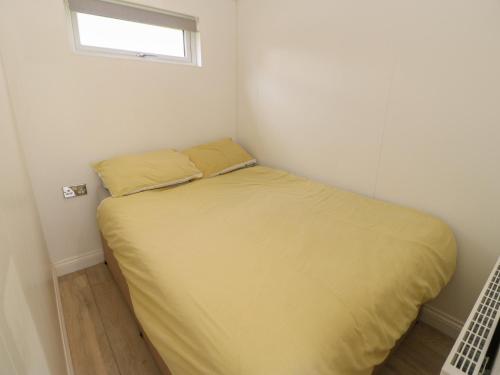 a bed in a small room with a yellow blanket at Roseberry Pod in Yarm