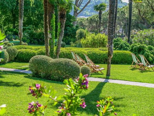 a garden with chairs and bushes and palm trees at Hotel Marko in Portorož