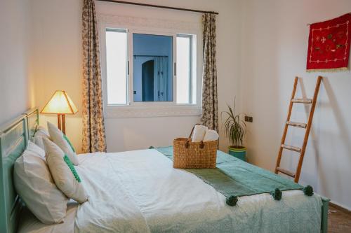 a bedroom with a bed with a window and a ladder at Dar Sultana Guesthouse Surf Morocco in Tamraght Oufella