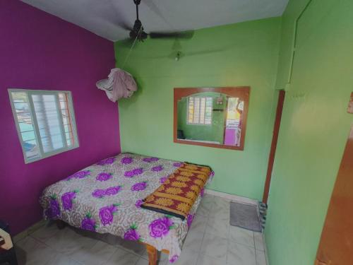 a bedroom with a bed with purple and green walls at Kiran River View Guest House in Hampi