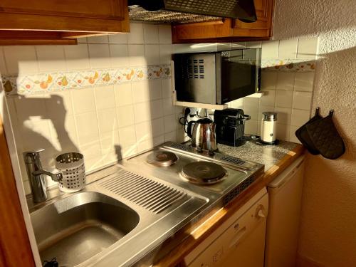 une petite cuisine avec un évier et un micro-ondes dans l'établissement Studio cosy Centre station de ski La Rosière 1850 vue magnifique plein Sud, à Montvalezan