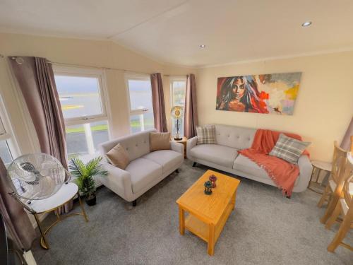 sala de estar con sofá y mesa en LakeDistrict Caravan by Sleepy en Millom