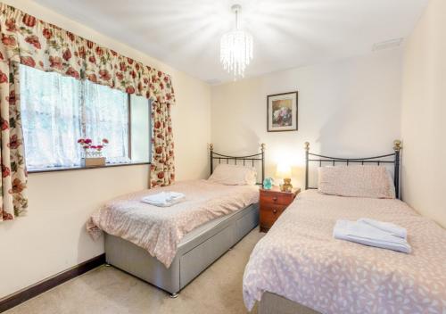 a bedroom with two beds and a window at The Carriage House Upcott House in Barnstaple