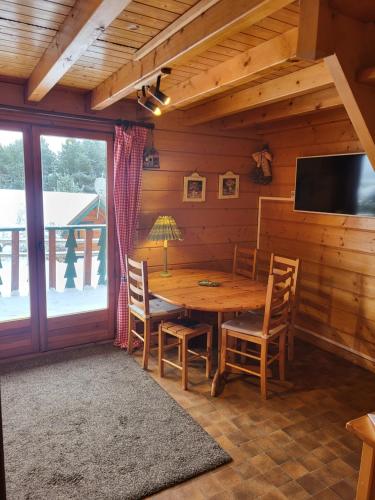 comedor con mesa, sillas y TV en Maison de bois finlandaise au pied des pistes, en Bolquere Pyrenees 2000