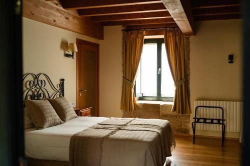 een slaapkamer met een bed en een groot raam bij Casa Rural Rectoral de Armariz in Nogueira de Ramuin