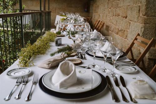 a long table with white plates and silverware on it at Casa Rural Rectoral de Armariz in Nogueira de Ramuin