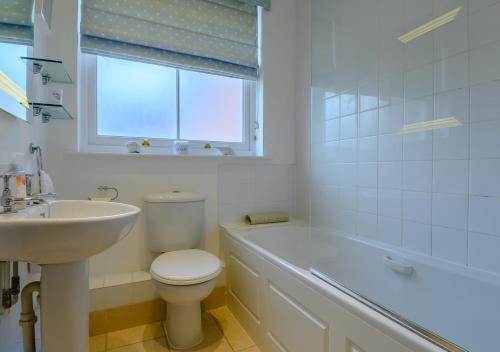 a white bathroom with a toilet and a sink at The Mews in Southwold