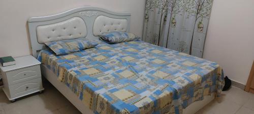 a bedroom with a bed with a blue and yellow quilt at VACATION HOME STAY AT SHRJAH DUBAI BORDER By mauon tourism in Sharjah