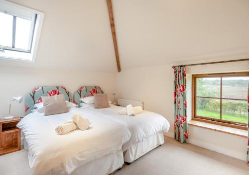 two beds in a white room with a window at Plough Cottage in Yoxford