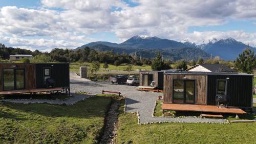a couple of tiny houses in a field with mountains at Puerta austral in Puelo